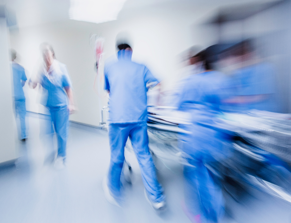 A photograph of doctors moving a hospital bed down a corridor