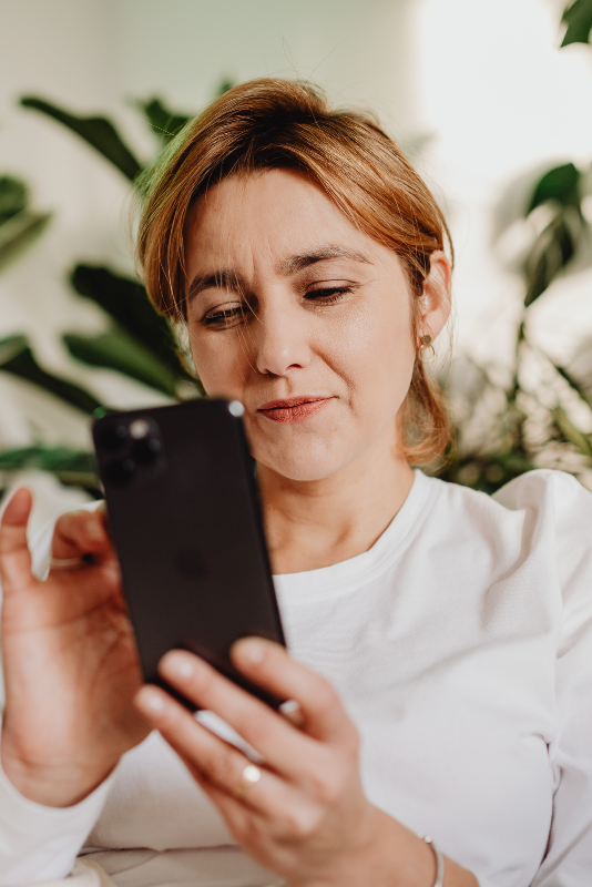 Woman holding smartphone in one hand and using the other to scroll or tap on the screen