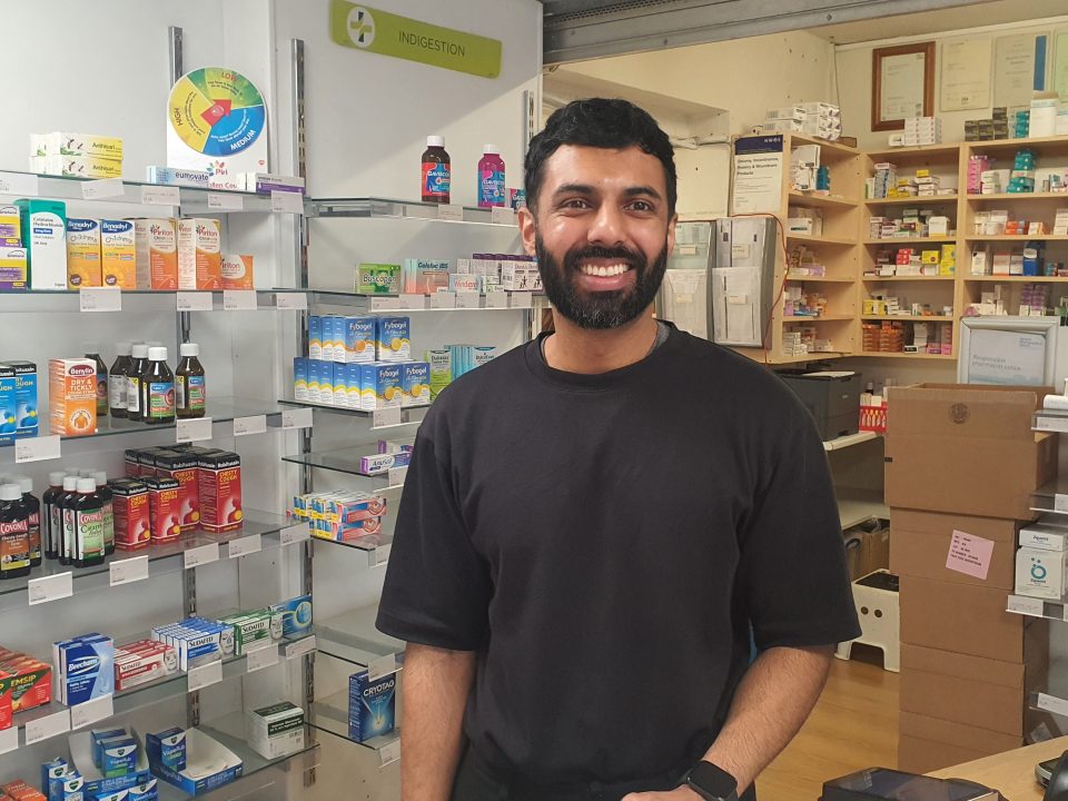 Photo of a pharmacist in front of shelves filled with medication
