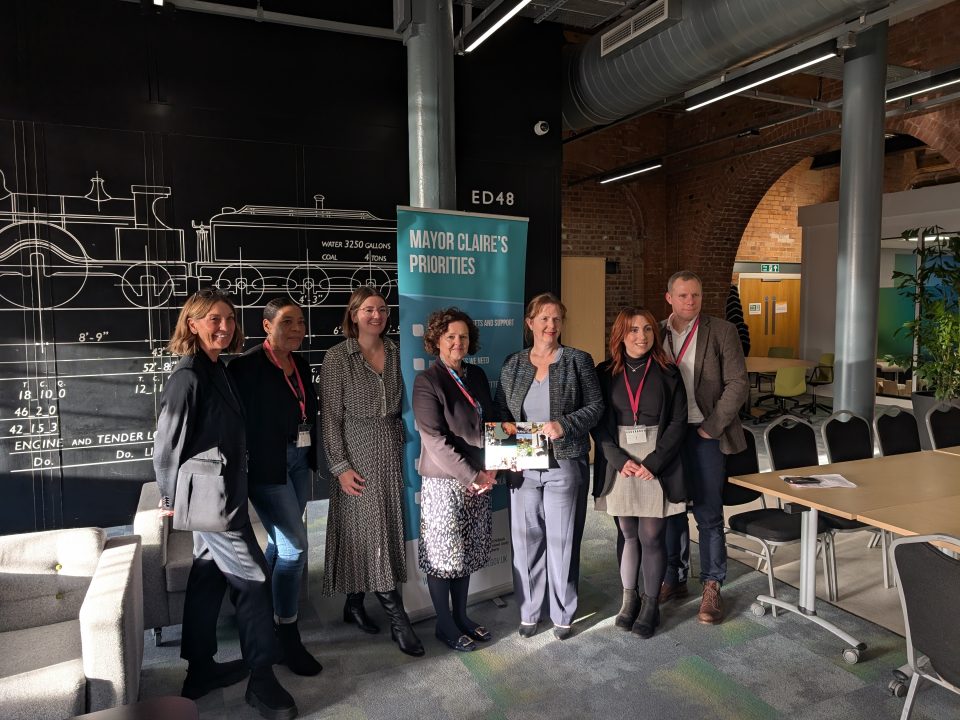Photo of representatives from the East Midlands Combined County Authority, Integrated Care Board and Department for Work and Pensions. They are holding a copy of the 'Get the East Midlands Working Plan'