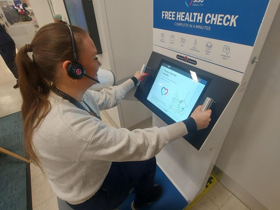 Woman seated at SISU Health Station undertaking a health check at Boots, Victoria Centre, Nottingham