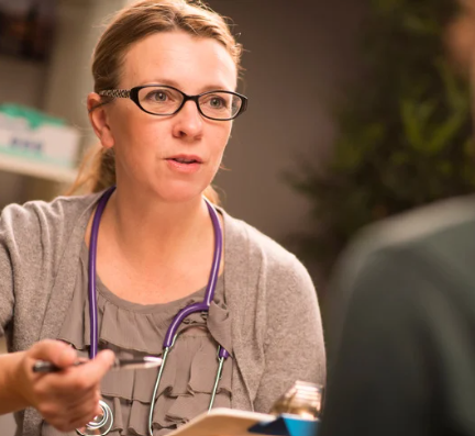 Female GP with a stethescope around her neck speaks to a patient