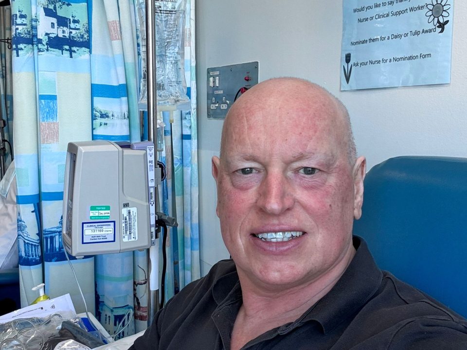 MAN SMILING AT CAMERA IN CLINICAL SETTING