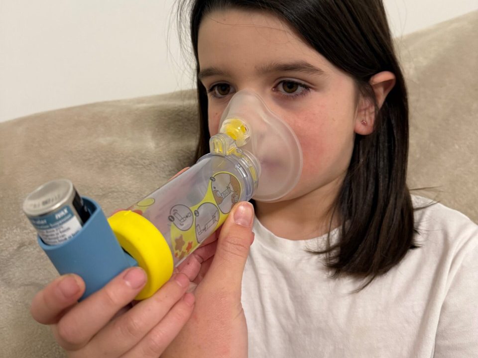 Girl using an asthma inhaler and spacer