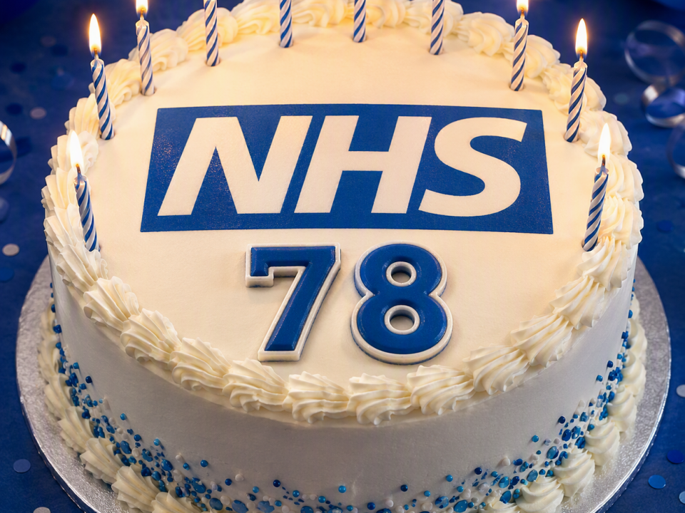 Photo of a white cake with candles and the NHS logo 78