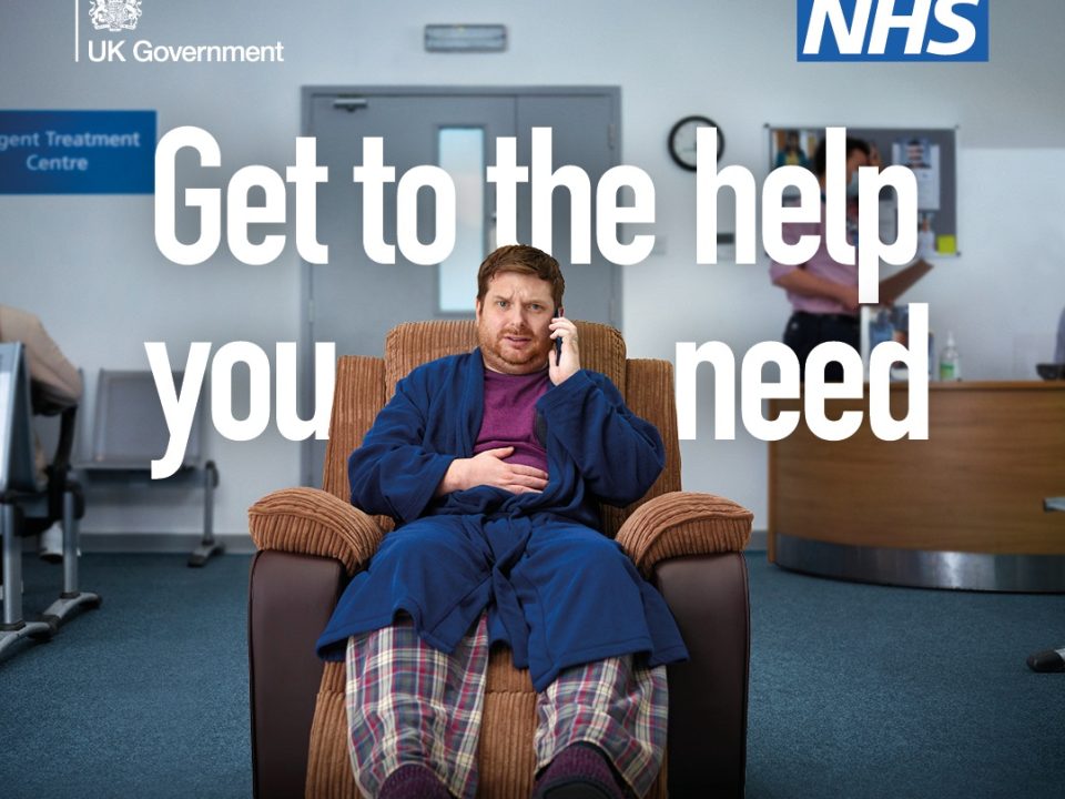 NHS and UK Government campaign image showing a person in pyjamas and a dressing gown sitting in an armchair in a healthcare waiting area while talking on a mobile phone. Large text reads: “Get to the help you need.”